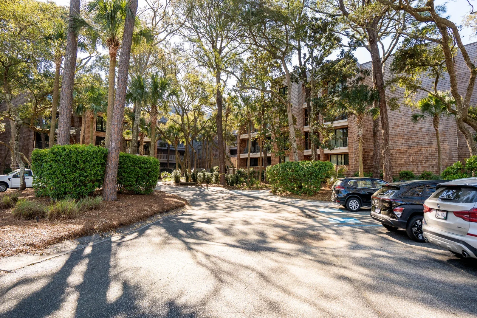 Multi-story brick condo complex with palm trees and parking in Kiawah Island vacation rental