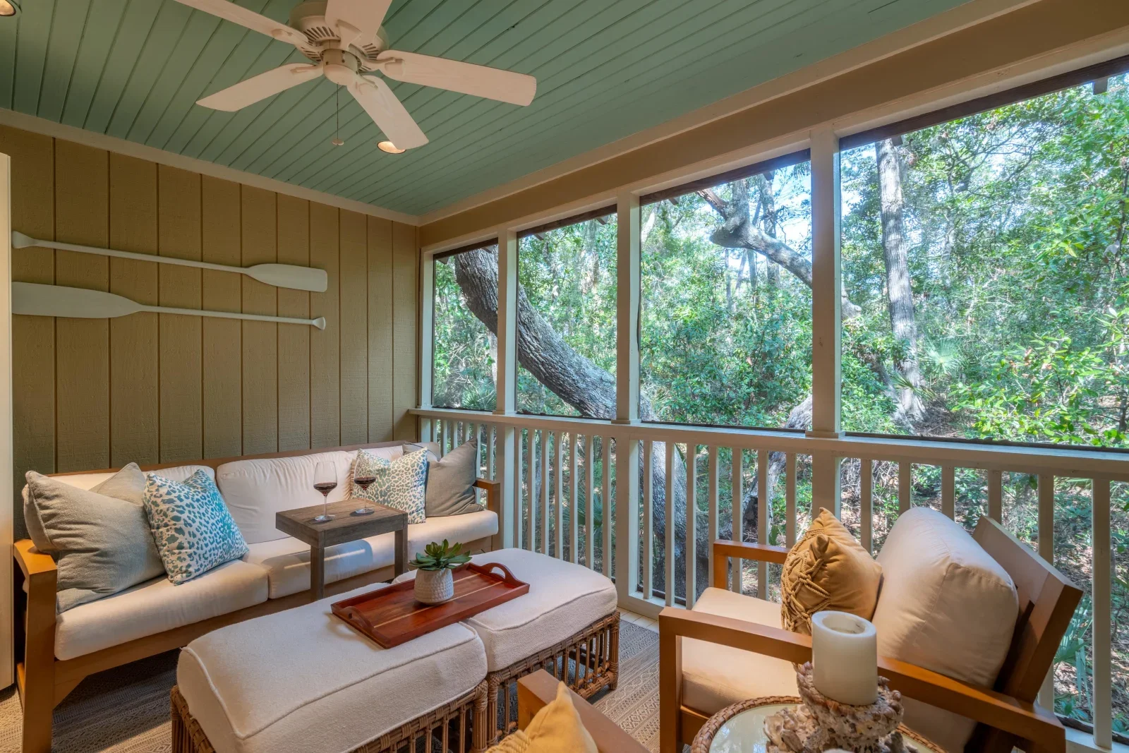 Enclosed porch with mint ceiling, comfortable seating, and tree views at Kiawah Island coastal retreat