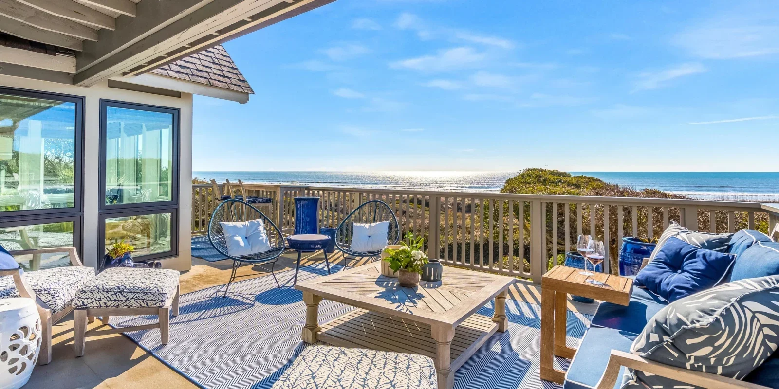 Oceanfront deck with modern seating and blue accents overlooking beach at Kiawah Island coastal property