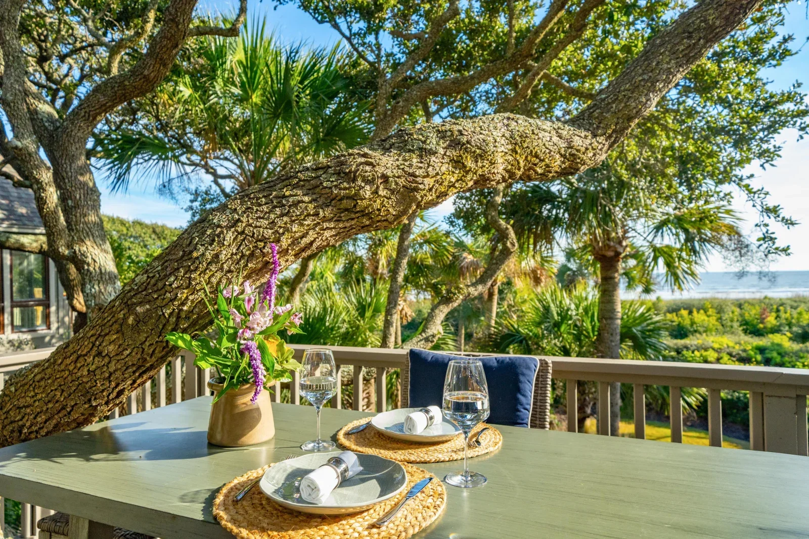 Waterfront patio dining setup with wine glasses and place settings under oak trees at Kiawah Island resort