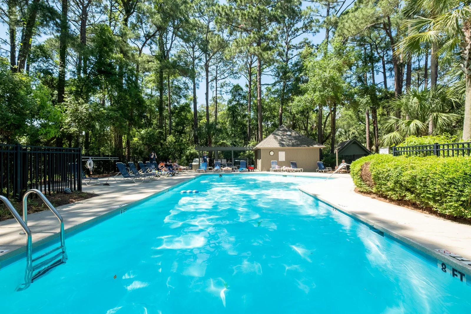 Resort-style community pool at a vacation rental home Kiawah Island SC with lounge chairs and palm trees