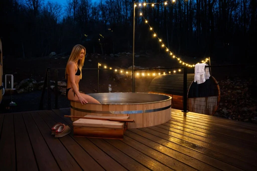 Outdoor hot tub on deck with string lights and forest backdrop at Royal Oak Retreat, base cabin for Shenandoah hiking trails