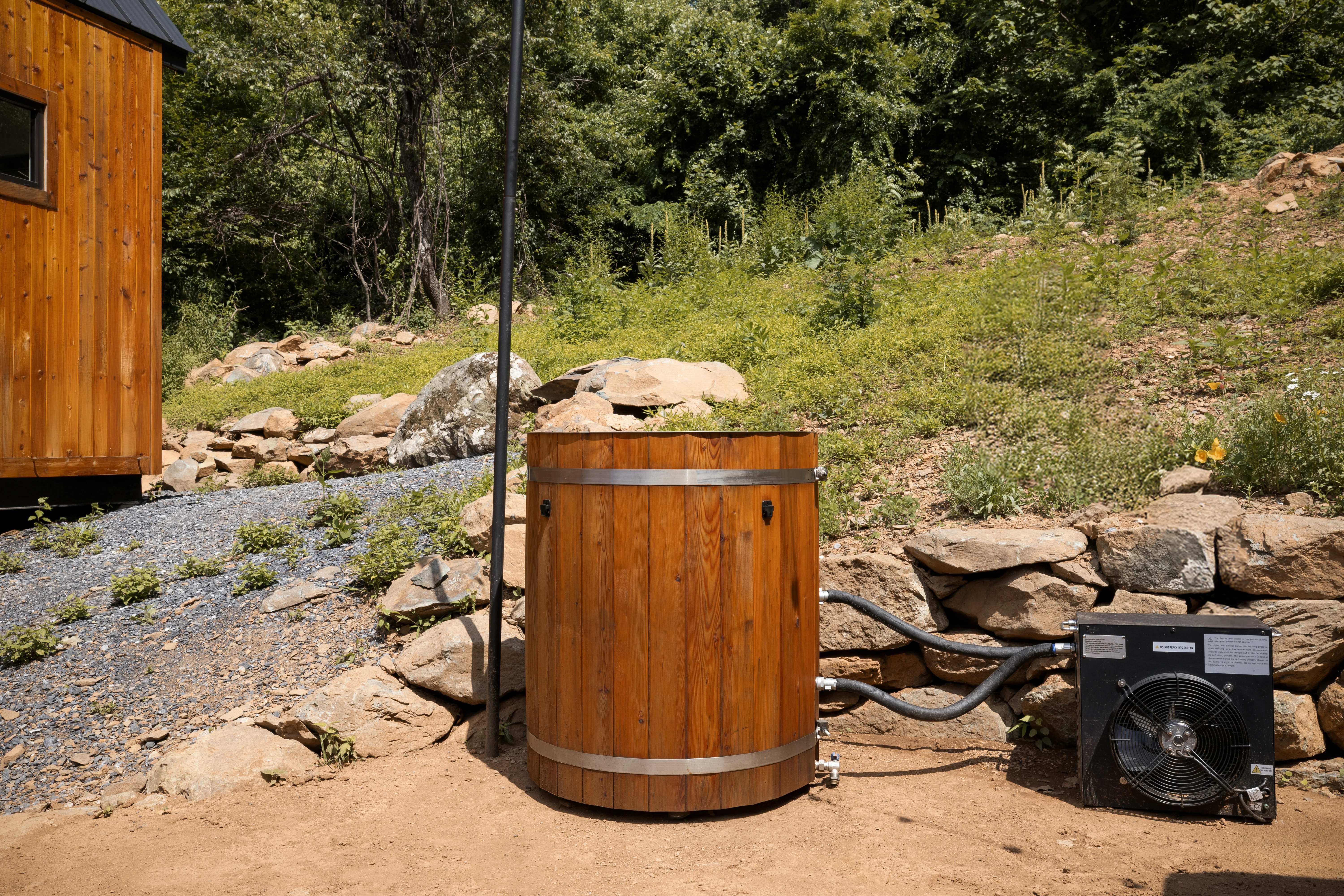 Rustic wooden hot tub on gravel pad with cabin and natural landscape at Royal Oak Retreat