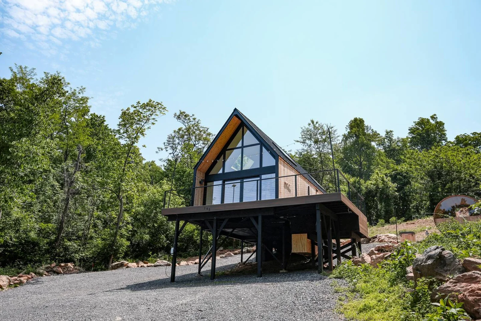 Modern A-frame cabin with wood accents and large windows in a forest setting at Royal Oak Retreat