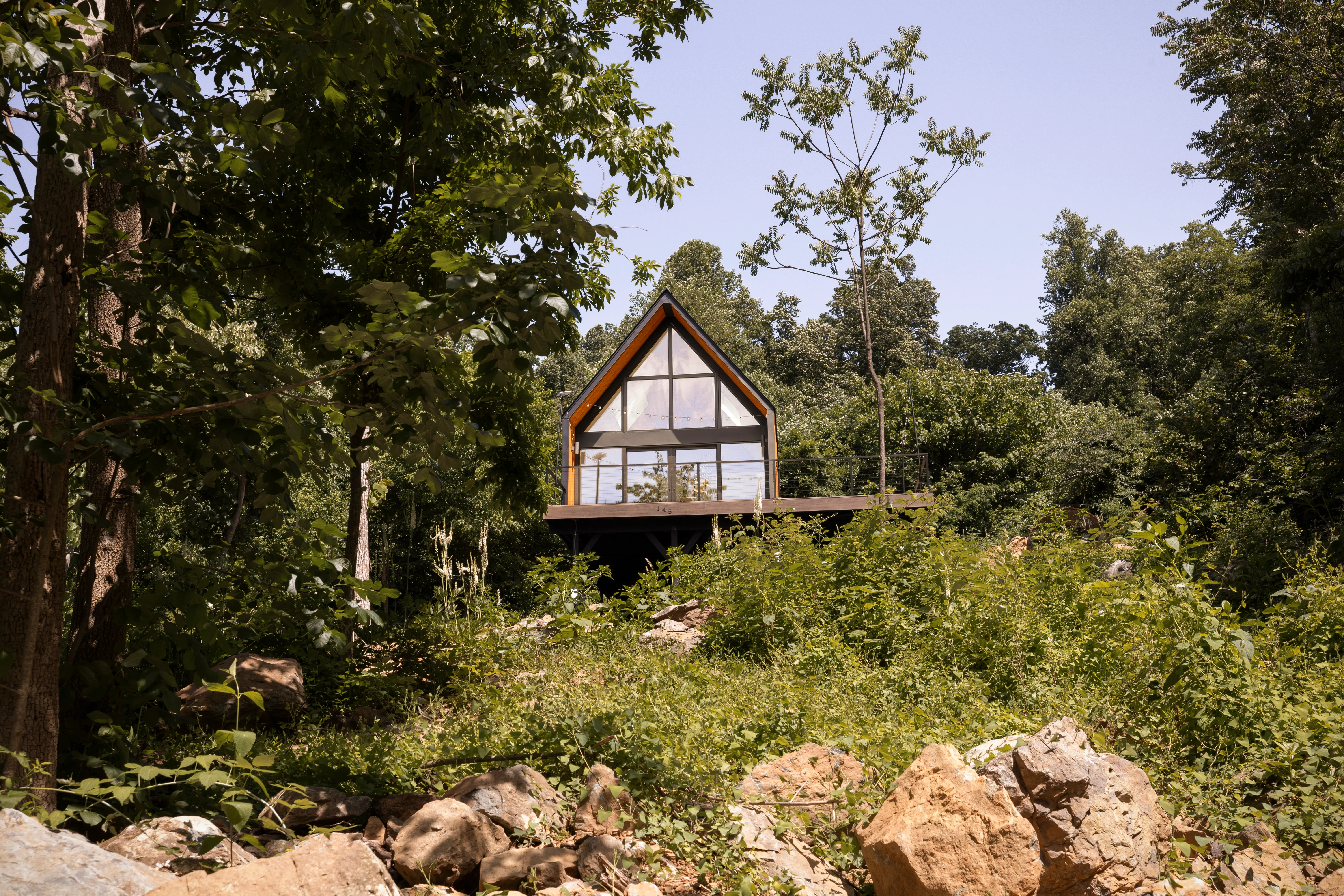 Modern treehouse with peaked roof and windows overlooking forest woodland at Royal Oak Retreat