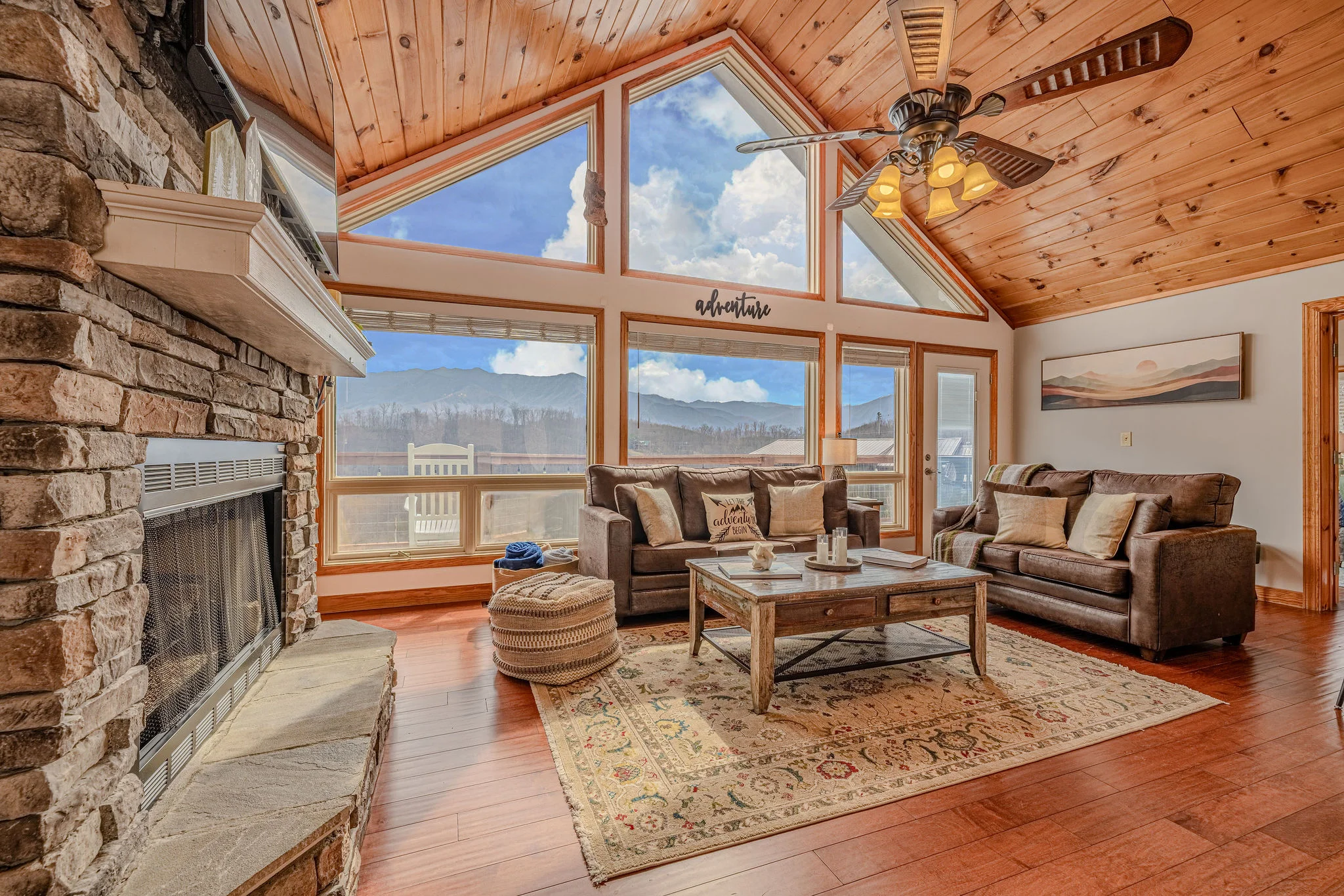 Gatlinburg cabin living room with vaulted wood ceilings, stone fireplace, and mountain view windows at Summit View Lodge