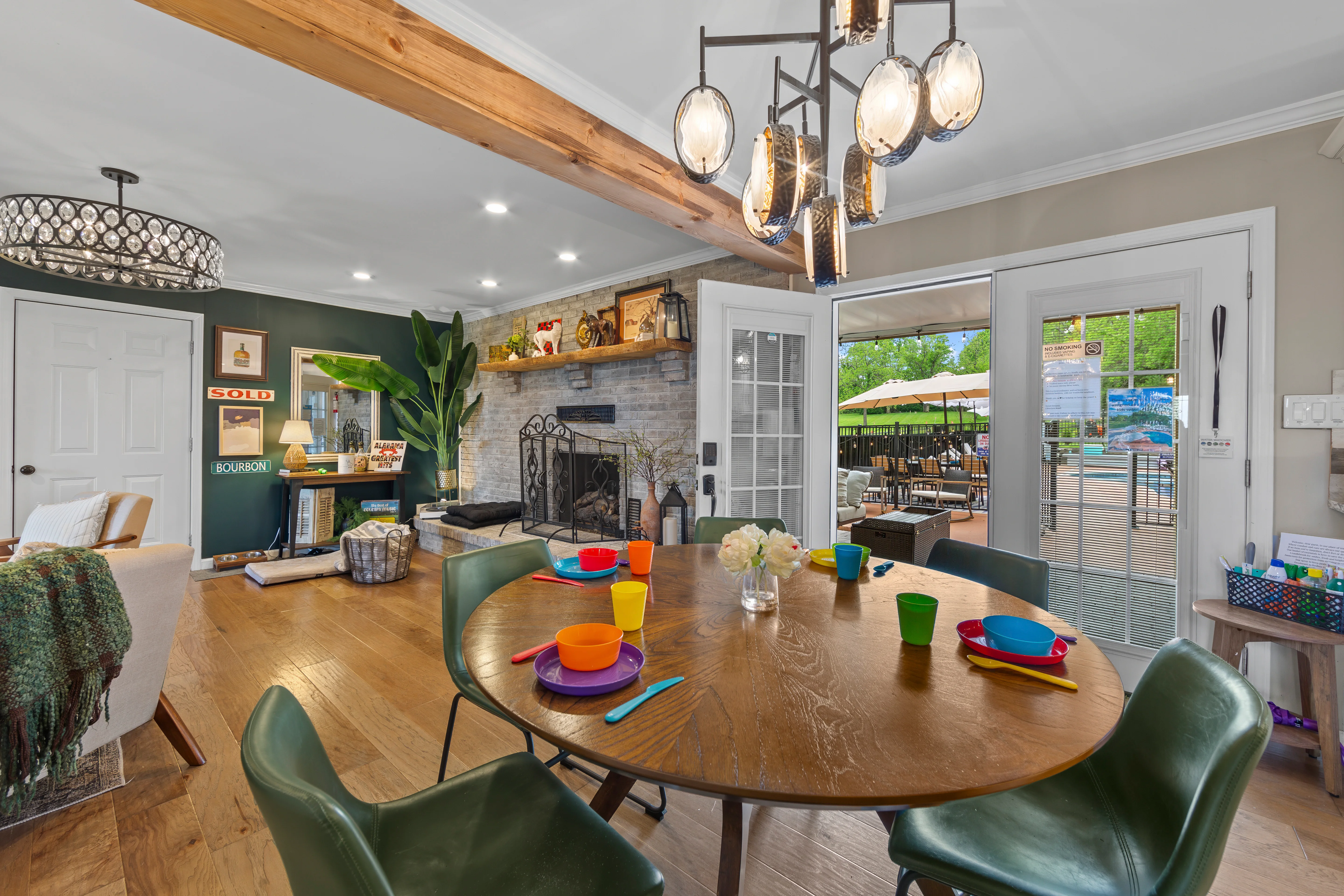 Modern dining room with wooden round table, green chairs, and exposed beams at Glencairn Knoll