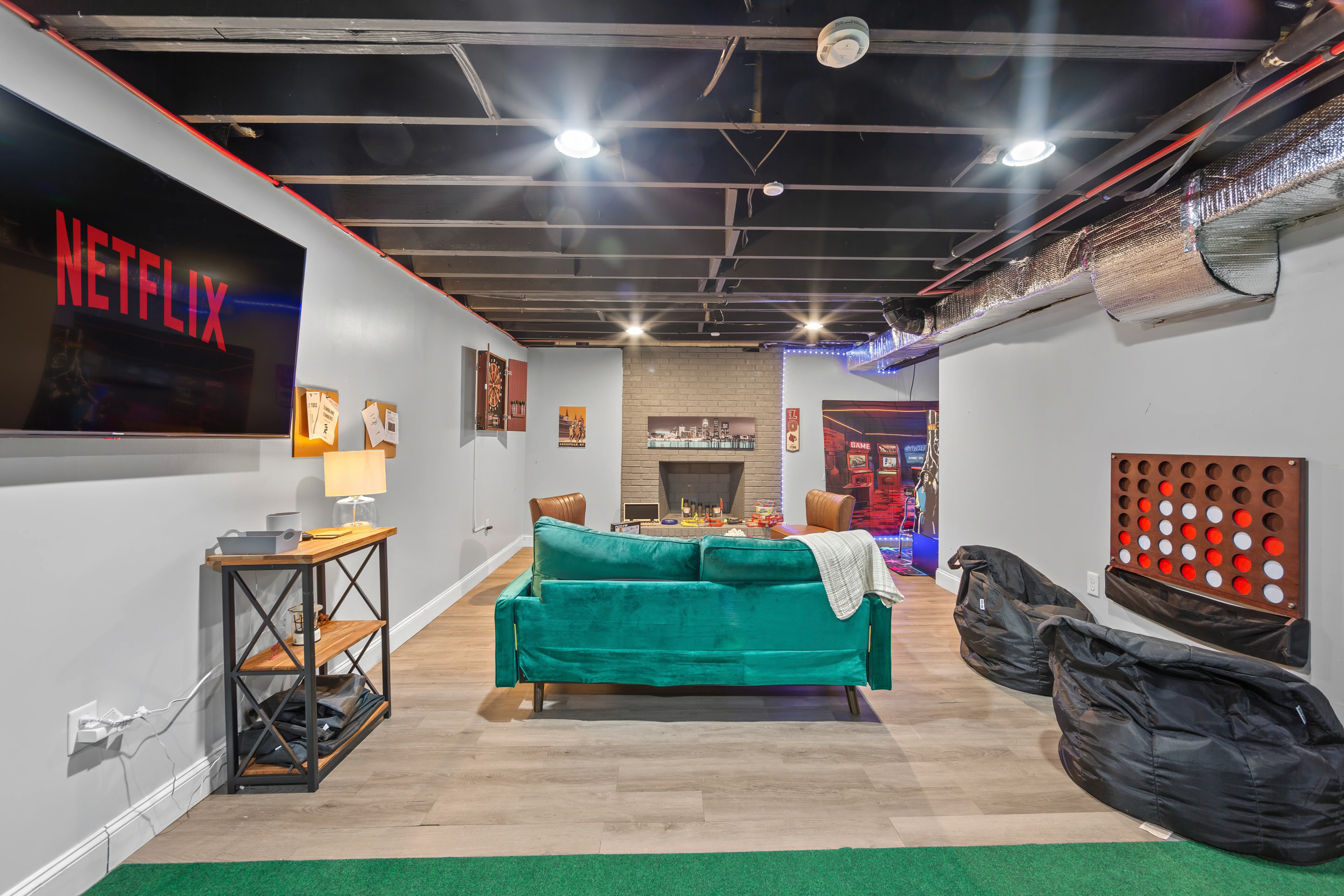 Modern basement entertainment room with turquoise sofa, fireplace, and games at La Grange rental