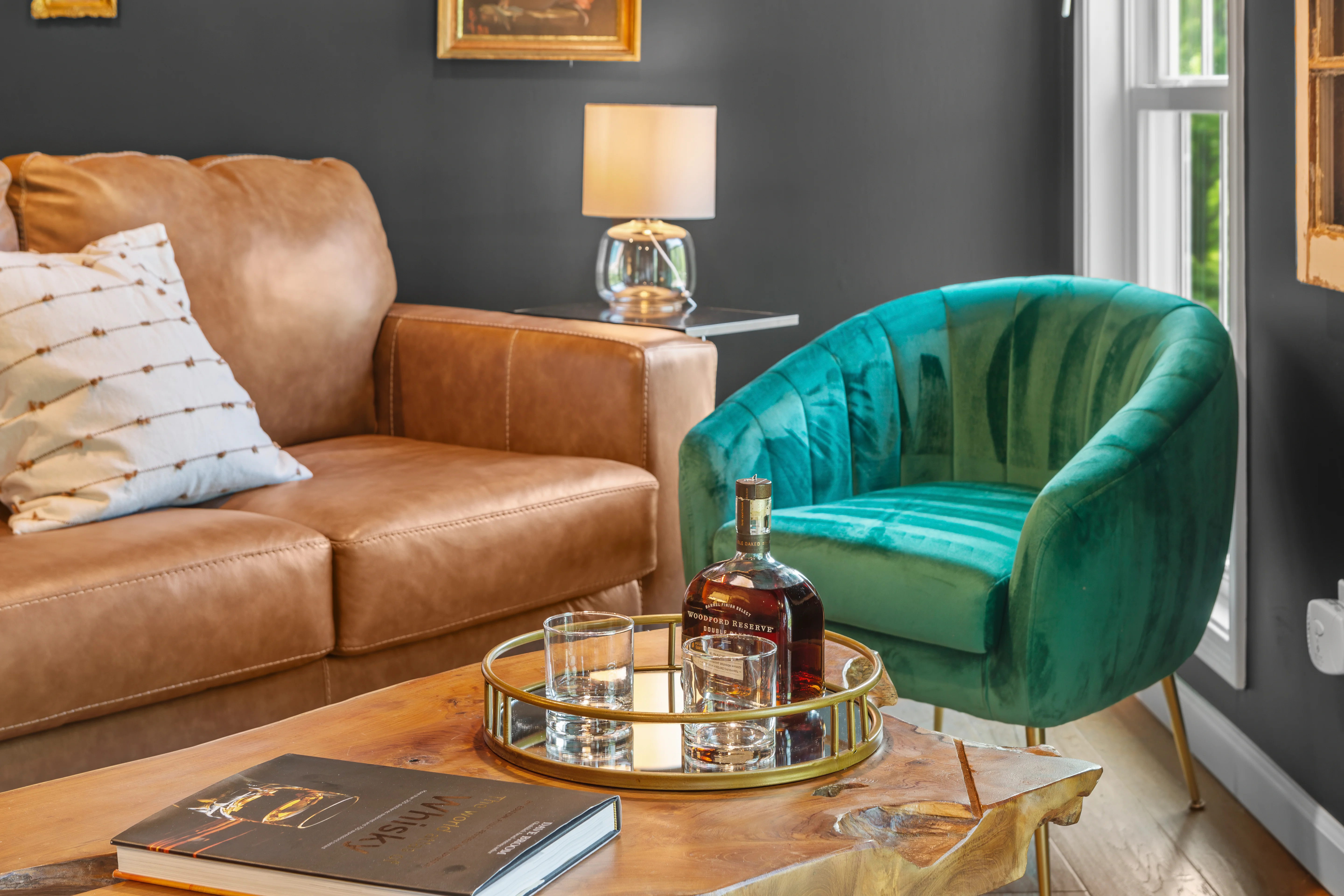 Luxury living room with tan leather sofa and emerald velvet armchair at Glencairn Knoll