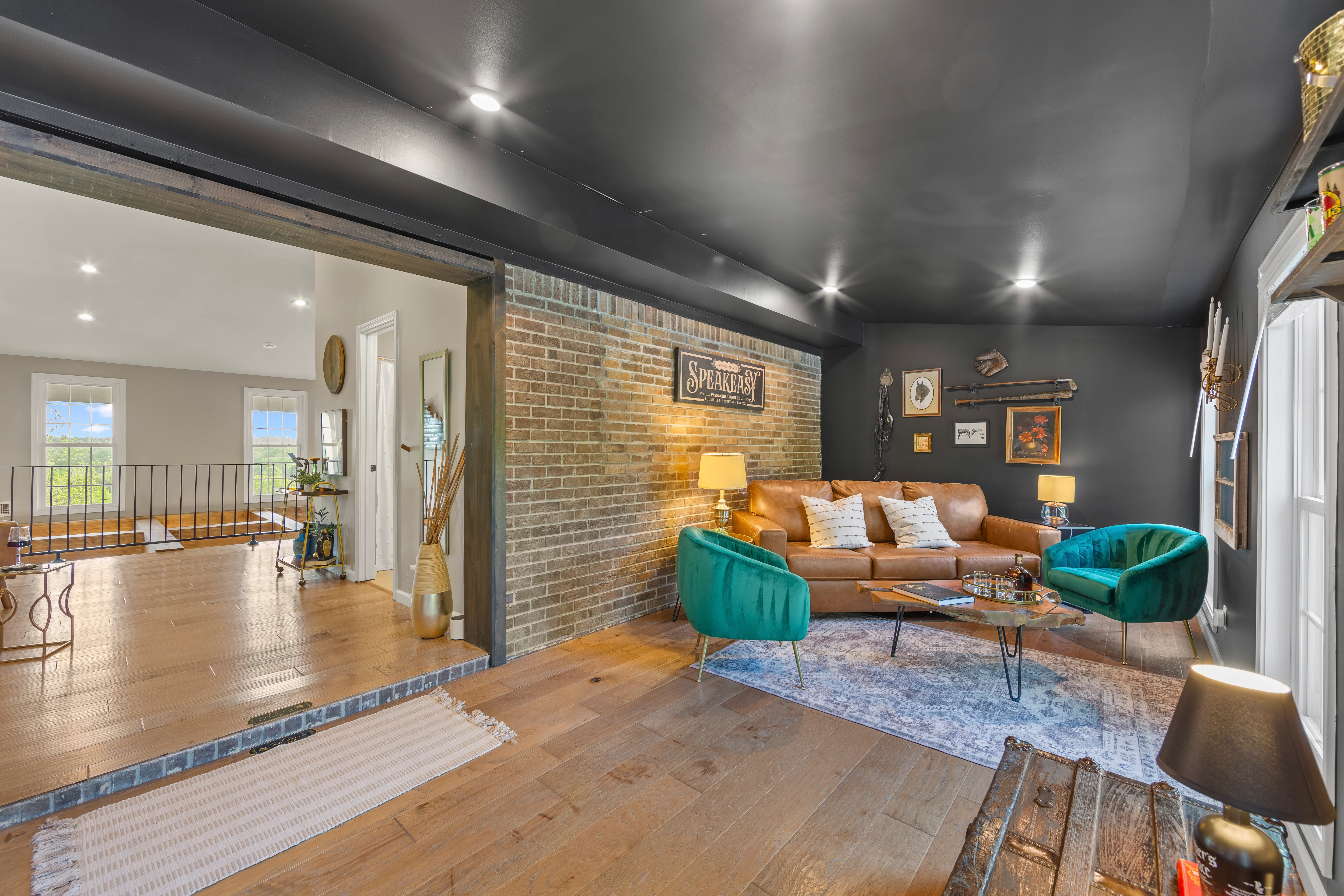 Modern open-concept living room with exposed brick, leather sofa, and turquoise accents at Glencairn Knoll