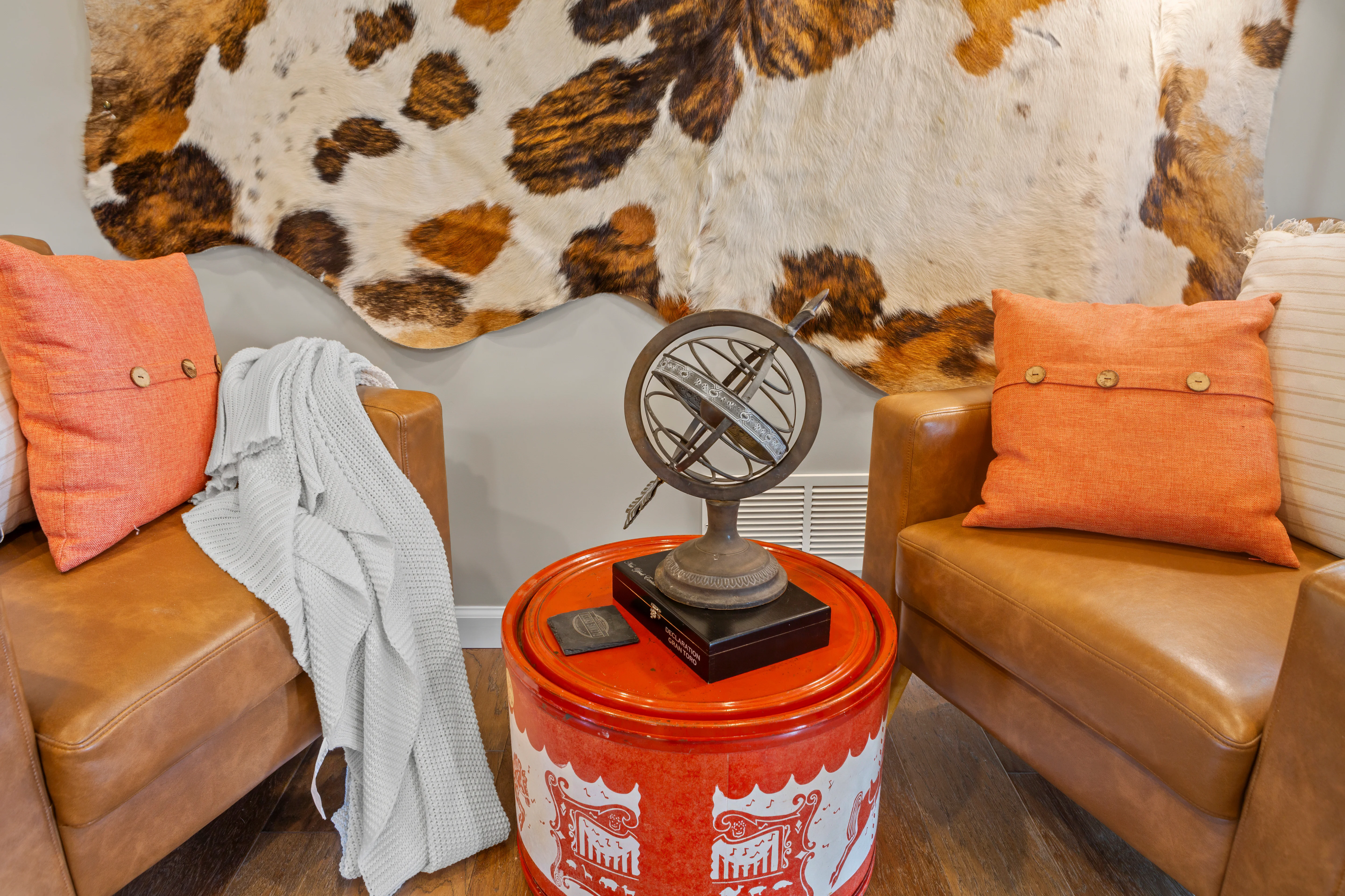 Tan leather seating with coral accents and cowhide headboard in living room at Glencairn Knoll